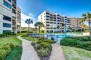 A hotel with multiple floors, a swimming pool, and well-maintained landscaping. - Oceanfront Condo With Pool & Tennis - Balcony, AC, Wifi & Washer/dryer (Fernandina Beach)