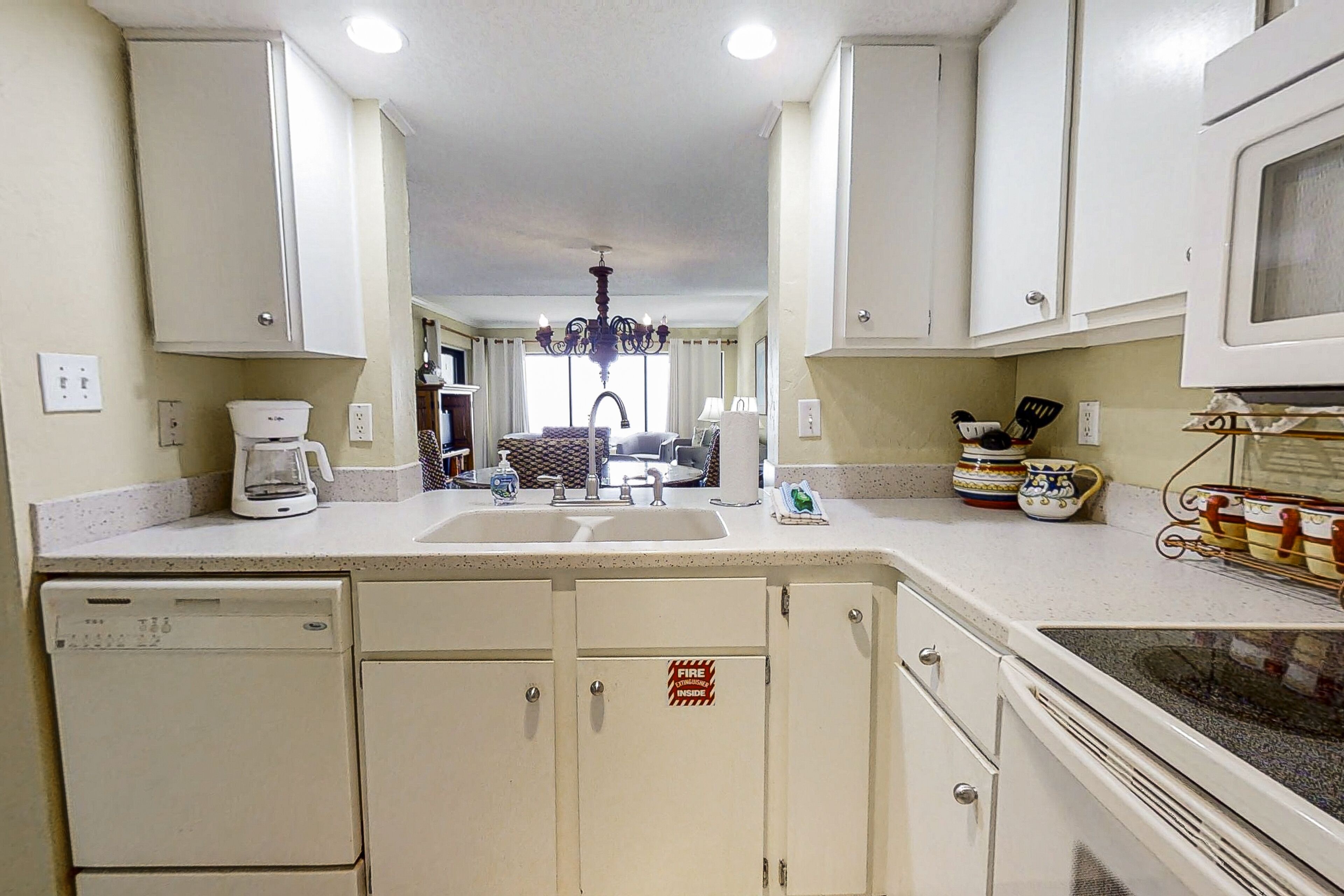 A kitchen with white cabinets, a dishwasher, a microwave, and a coffee maker.