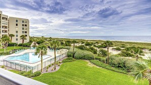 A resort with a swimming pool, lush greenery, and a view of the beach. - Oceanfront Condo With Pool & Tennis - Balcony, AC, Wifi & Washer/dryer (Fernandina Beach)