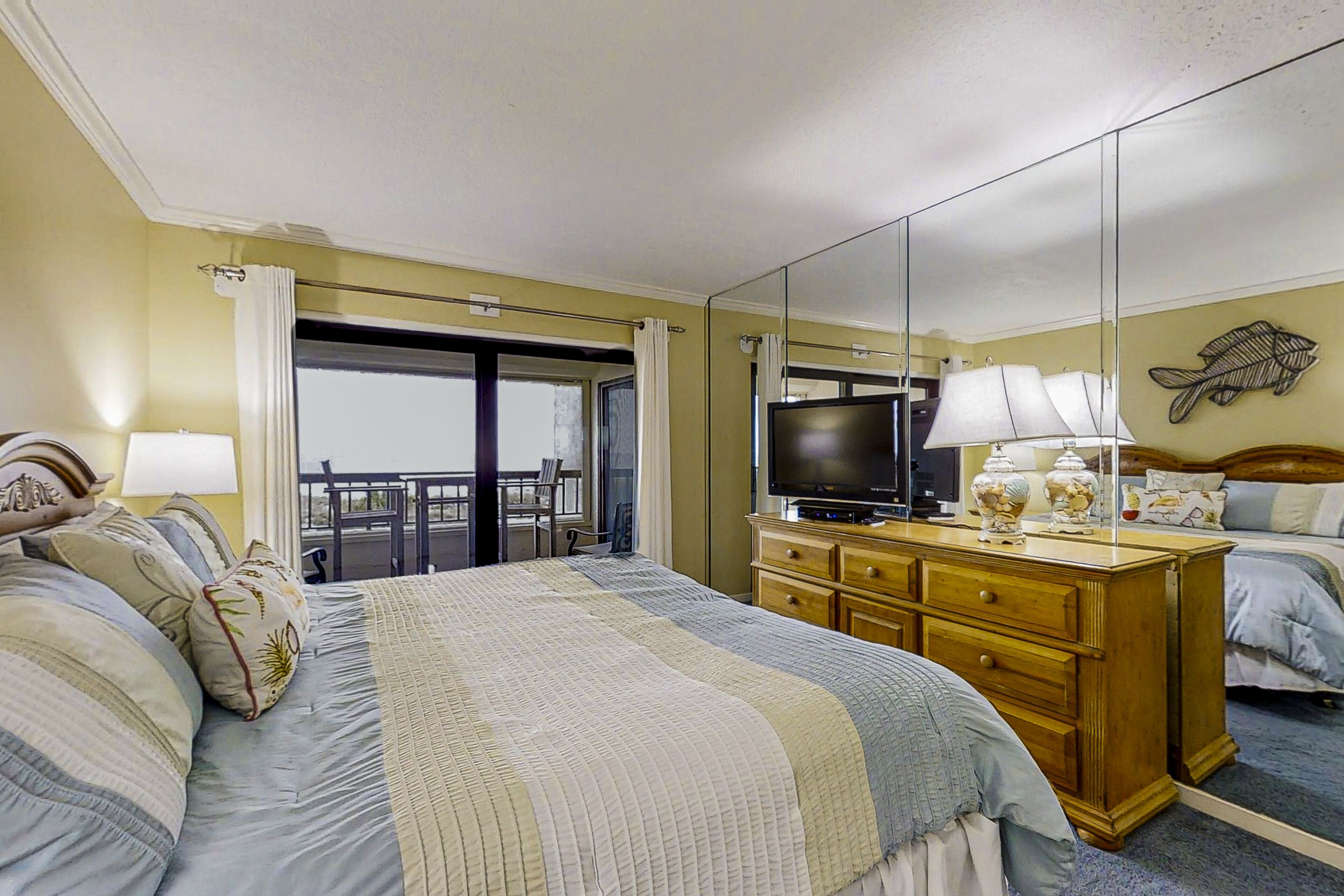 Een hotelkamer met een groot bed, een dressoir, een televisie en een balkon met uitzicht.