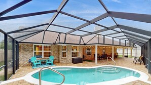 Una piscina exterior techada con un jacuzzi, rodeada de muros de ladrillo y puertas de cristal, y equipada con mobiliario de exterior.