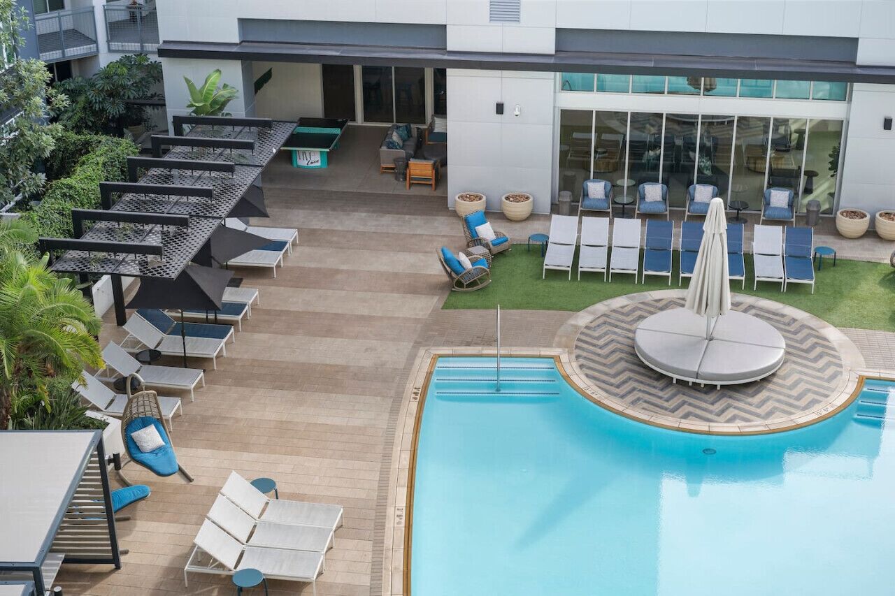 A rooftop pool area with lounge chairs, a small seating area, and a pool with a fountain.