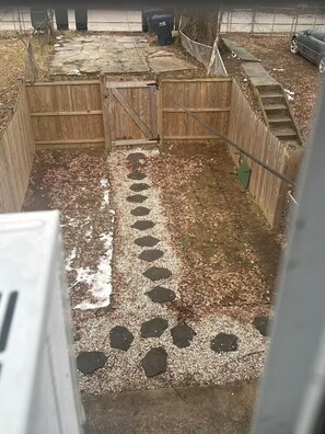 A fenced outdoor area with a concrete path leading to a wooden gate.