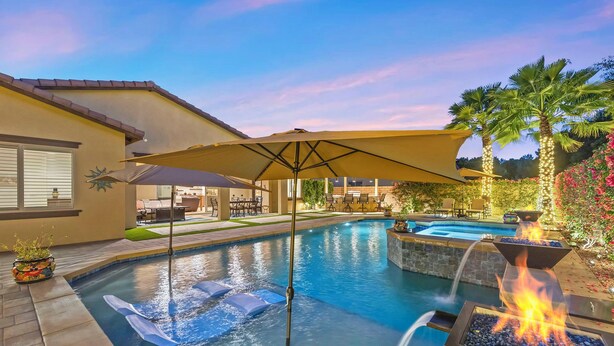 Ein Swimmingpool mit Feuerstelle, Sitzgelegenheiten im Freien und einer überdachten Terrasse.