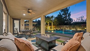 Ein Außenbereich mit Terrasse, Pool, Sitzgelegenheiten und Deckenventilator.