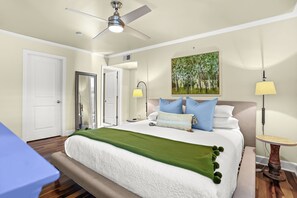 Habitación de hotel con cama, lámparas de noche, un cuadro y ventilador de techo.