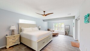 A bedroom with a large bed, a nightstand, a ceiling fan, and a window. - Updated Home With Private Pool, Patio, Central AC, & W/D (Palm Coast)