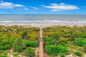 A beach with a wooden boardwalk leading to the shore, surrounded by dense greenery. - Third Floor Condo With Shared Pool, Free Wifi, Central AC, & Shared Tennis (St. Augustine)