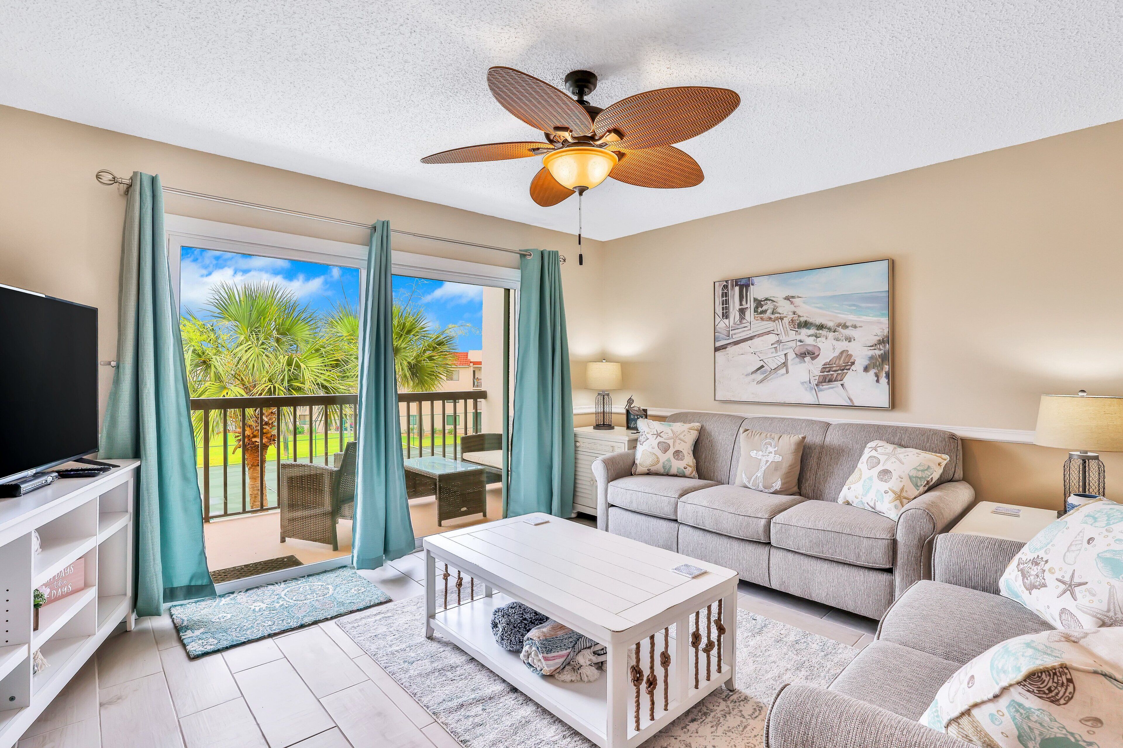 A living room with a TV, sofa, coffee table, and a ceiling fan.