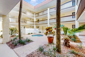 Un hotel de varios pisos con un patio central, piscina exterior y múltiples balcones.