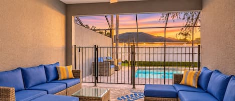 Eine überdachte Terrasse mit zwei blauen Sofas, einem Glastisch und einem Deckenventilator.
