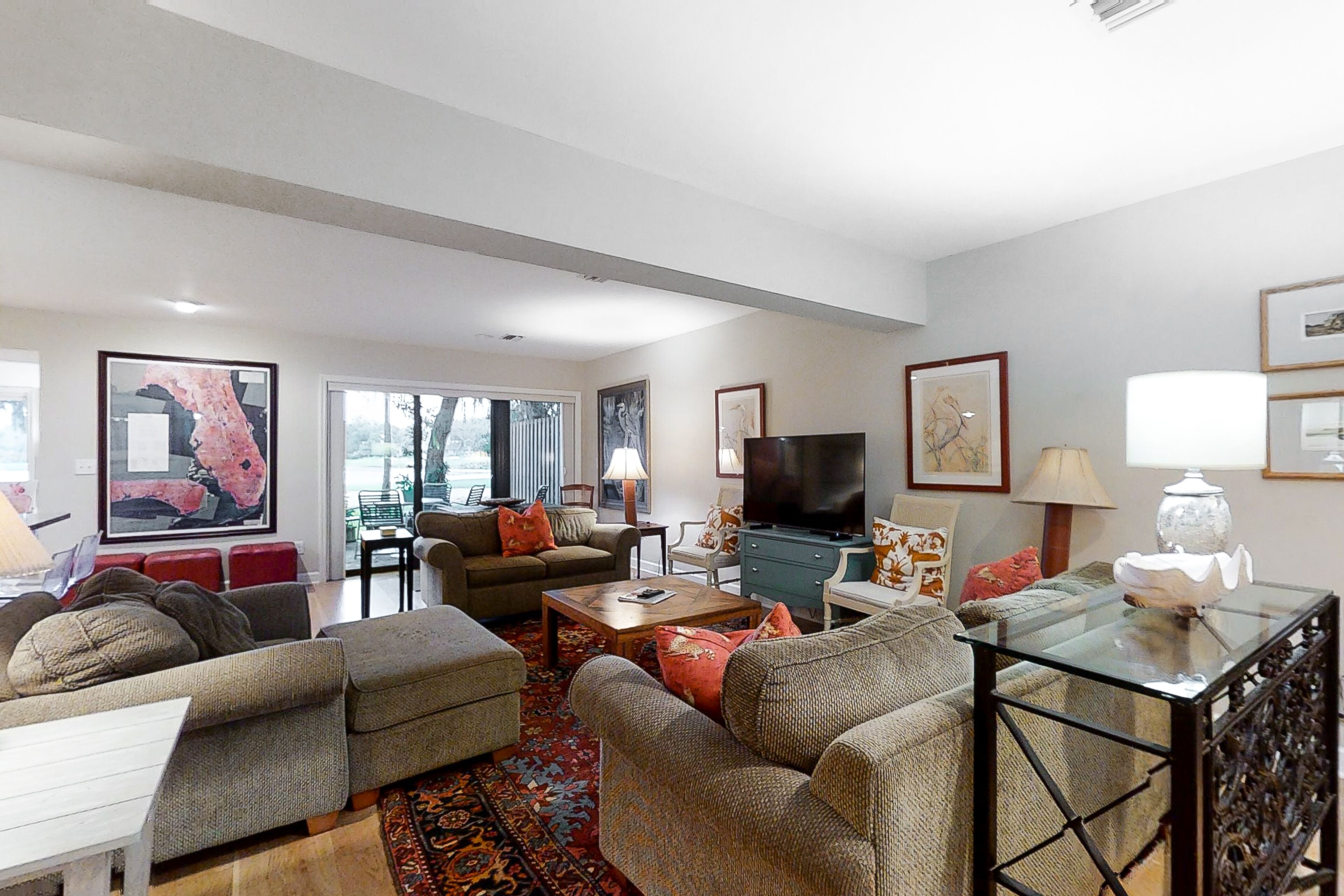 A spacious living room with a large flat-screen TV, multiple sofas, a coffee table, and a glass-top table.