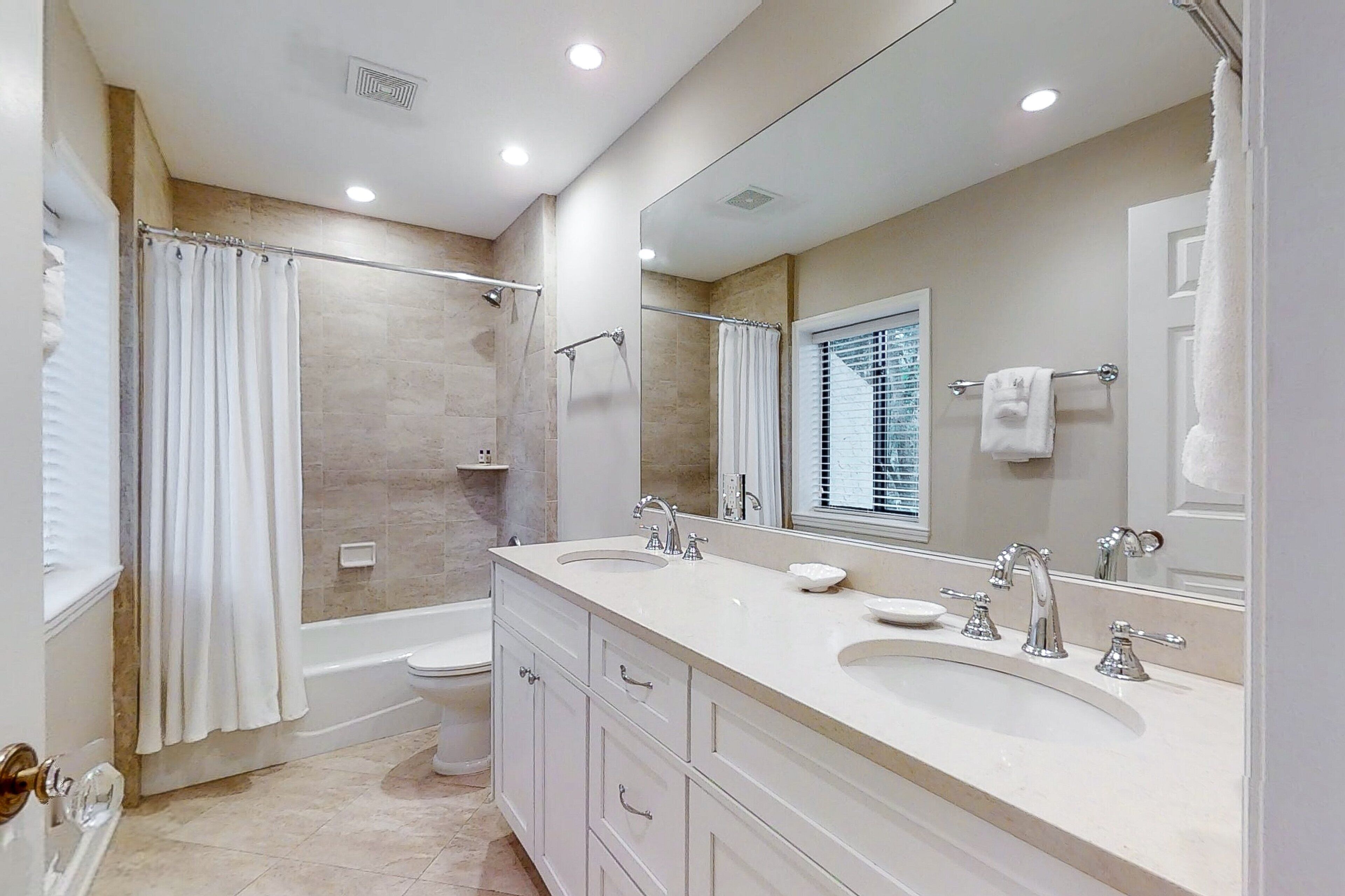 A modern bathroom with a double sink vanity, a bathtub, and a shower.
