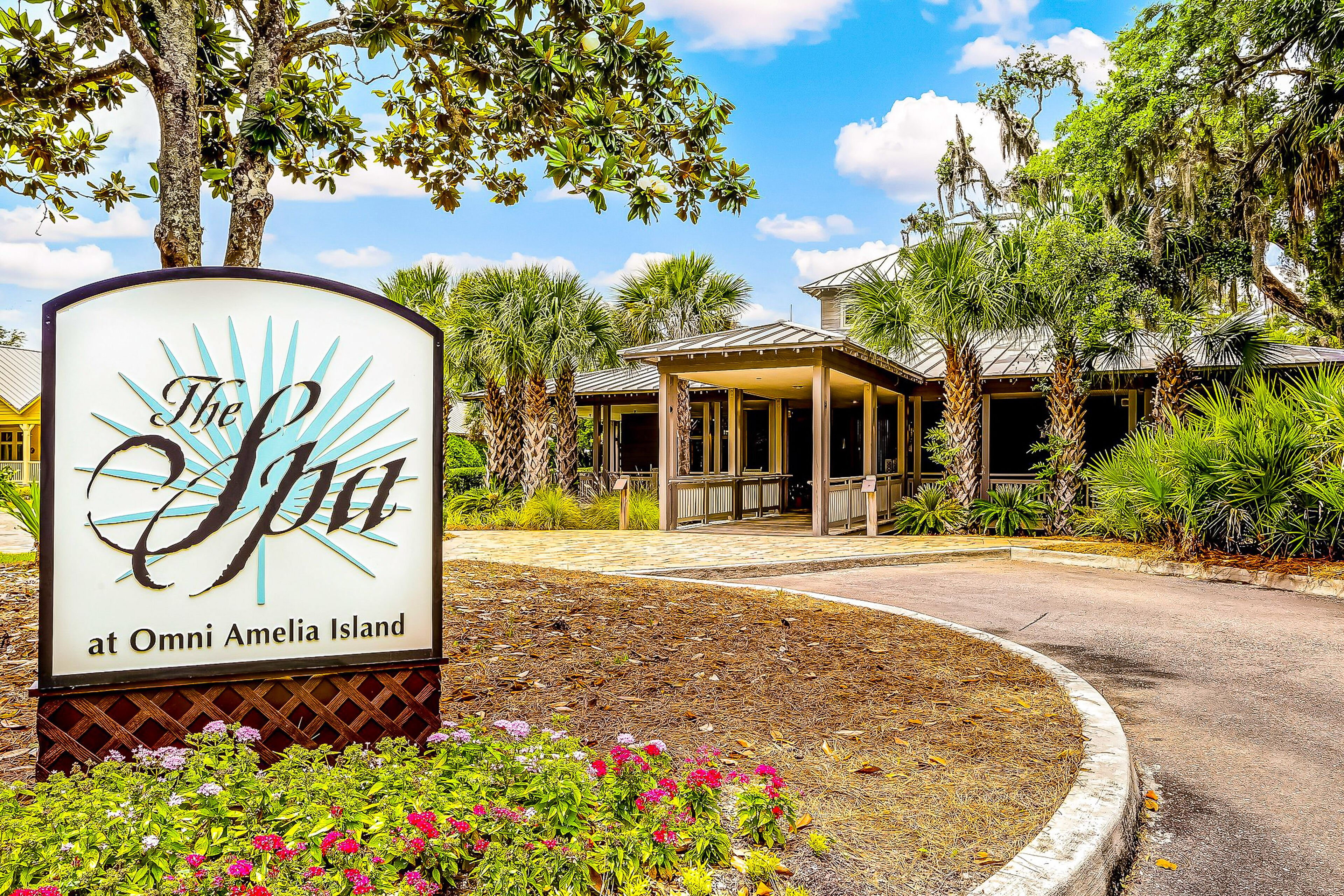 A sign for "The Spa at Omni Amelia Island" with a covered entrance and surrounding tropical landscaping.