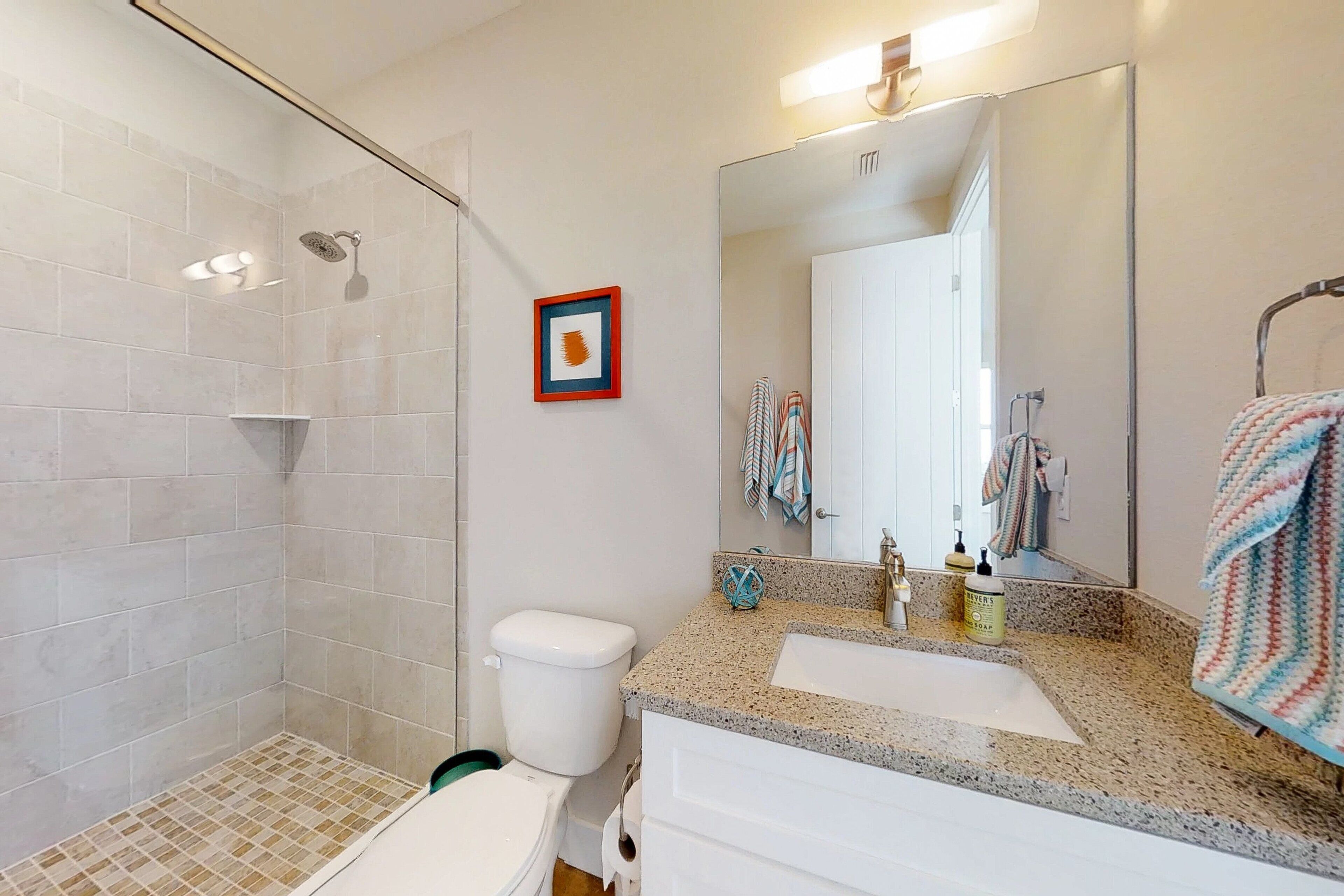 Un baño con ducha, inodoro y dos lavamanos con espejo.