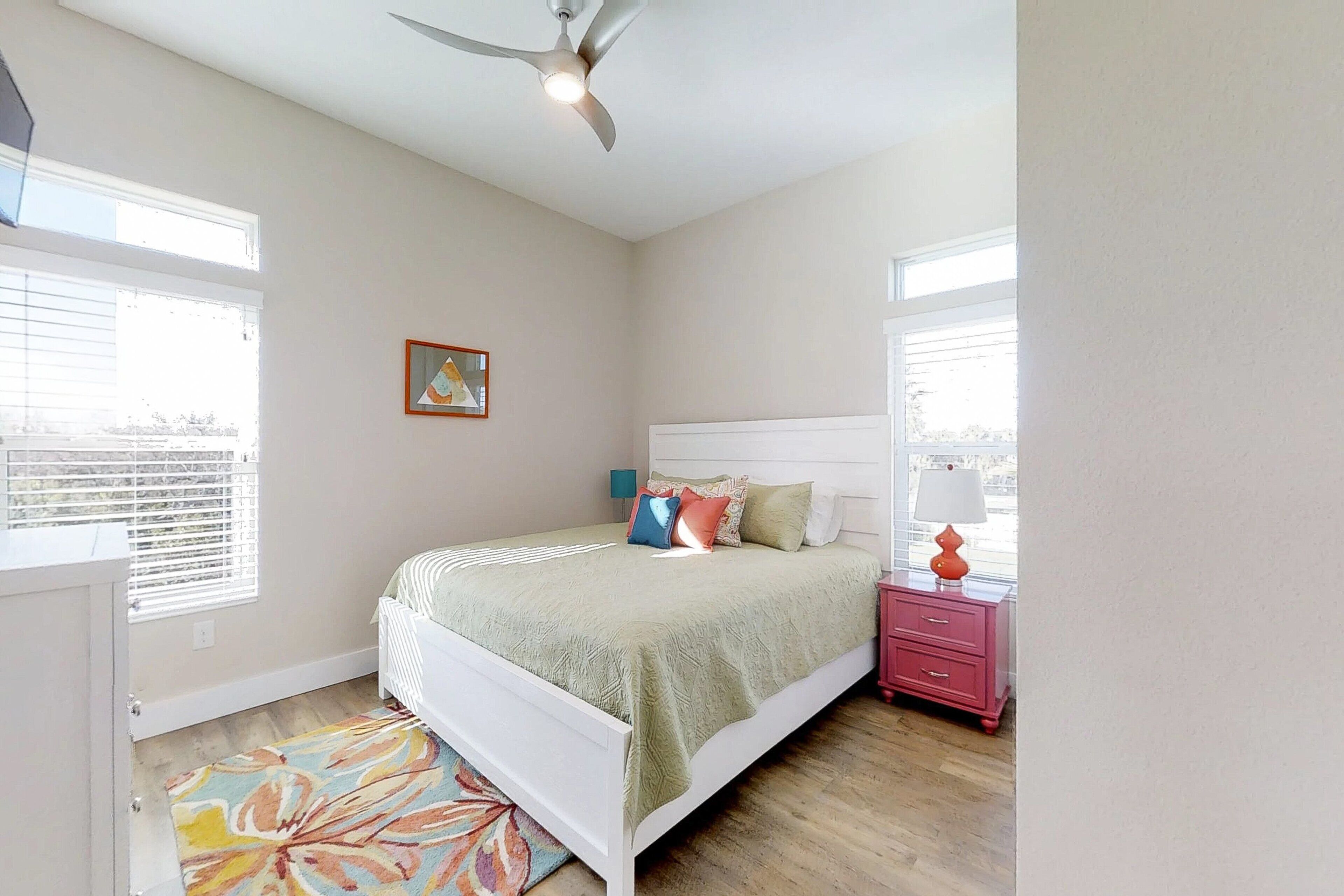 A bedroom with a bed, bedside table, and a ceiling fan.