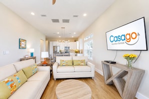 Una sala de estar moderna con un sofá, una mesa de centro y una pantalla de televisión mostrando 'Casago Vacation Rentals'.