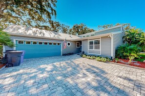 A two-story house with a garage, a paved driveway, and a small garden with plants and flowers. - Updated Home With Great Outdoor Space - Close to the Beach (St. Augustine)