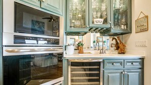 A kitchen with a built-in oven, a refrigerator, and a glass-fronted cabinet with various dishes. - Tranquil Coastal Home With Ocean Views, Beach Access, Balcony & Shared Pool (Fernandina Beach)