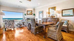 A dining area with wicker furniture, a fireplace, and a view of the ocean. - Tranquil Coastal Home With Ocean Views, Beach Access, Balcony & Shared Pool (Fernandina Beach)