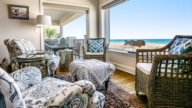A room with wicker furniture, a glass table, and a view of the beach. - Tranquil Coastal Home With Ocean Views, Beach Access, Balcony & Shared Pool (Fernandina Beach)