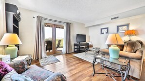 Una sala de estar con sofá, sillones, una mesa de centro, televisor y mueble para televisión.
