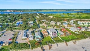 Zona residencial costera con casas, una playa y una gran masa de agua al fondo.