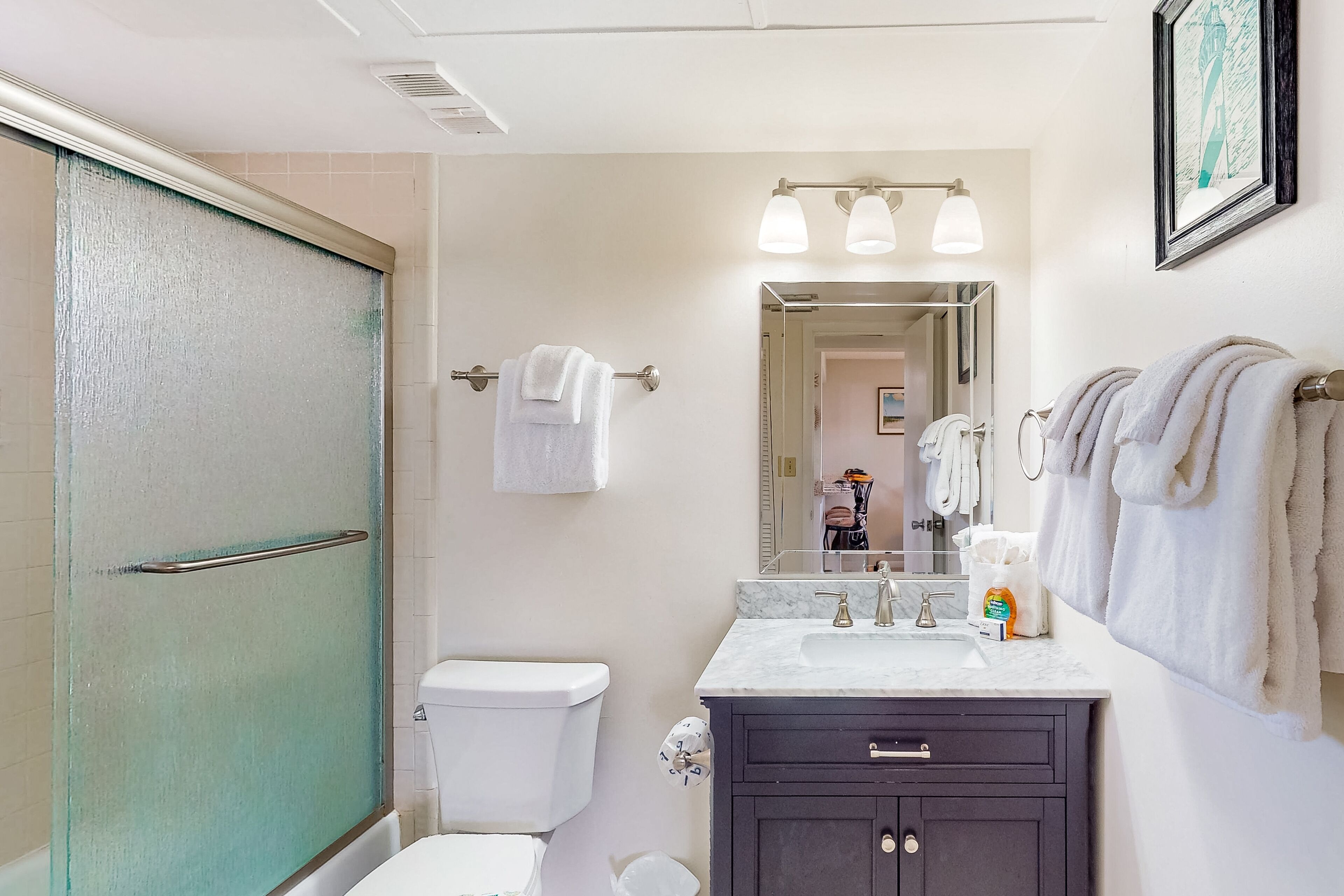 Un bagno con il water, lavandino, mobile lavabo e zona doccia.