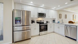 A modern kitchen with stainless steel appliances, white cabinetry, and recessed ceiling lights. - Spacious Townhouse With Private Balcony, Waterview, Pool and Wifi (Palm Coast)