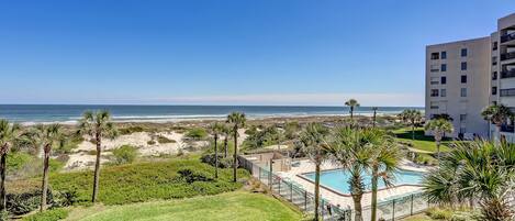 Un hôtel doté d’une piscine, de palmiers et offrant une vue sur la plage et l’océan.