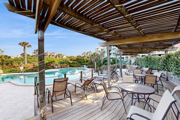 A poolside area with wooden deck, lounge chairs, and a pool. - Waterfront Condo With Balcony, Views, Pool & Tennis (Fernandina Beach)