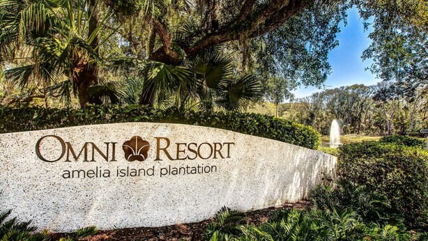 Schild für Omni Resort Amelia Island Plantation mit einer natürlichen Landschaft und einem Springbrunnen im Hintergrund.