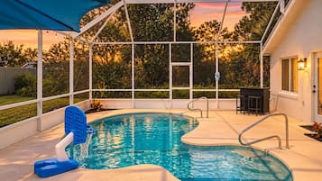 Una piscina con zona cubierta, escalera y área de descanso con mesa y sillas.