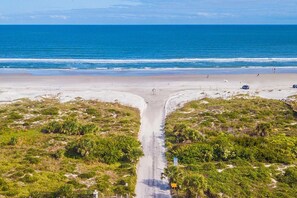 A beach with a road leading to the shore, surrounded by greenery. - Steps Away From Beach & Pool a Two-story Townhome on Anastasia Island (St. Augustine)