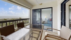 A balcony with wicker furniture and a glass table overlooking the beach. - Third-floor Oceanfront Condo With Balcony, W/d, Pool & Tennis (Fernandina Beach)