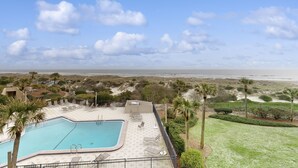 A swimming pool with lounge chairs, a view of the beach, and palm trees. - Third-floor Oceanfront Condo With Balcony, W/d, Pool & Tennis (Fernandina Beach)