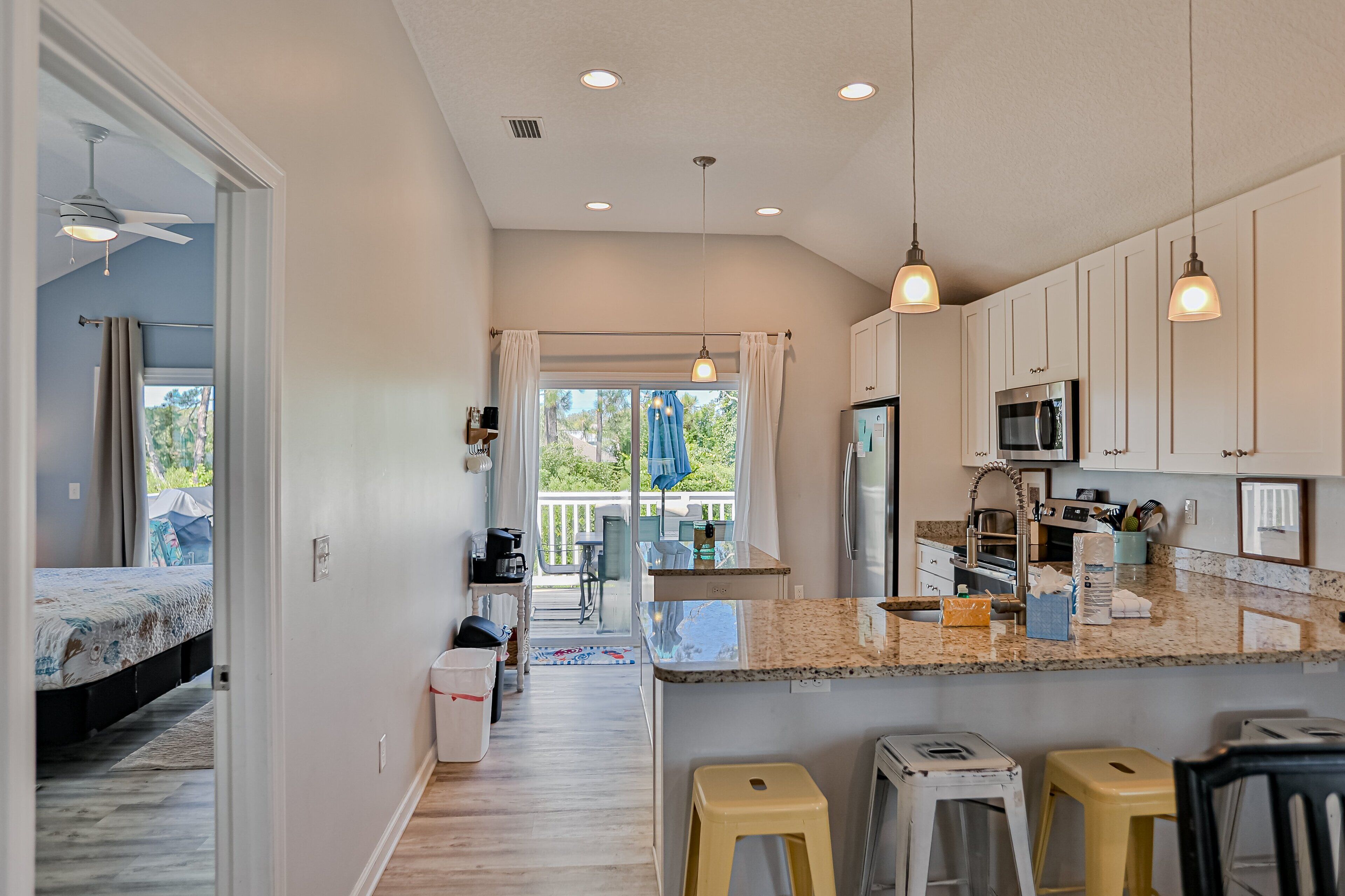 A modern kitchen with white cabinets, a granite countertop, and pendant lighting.