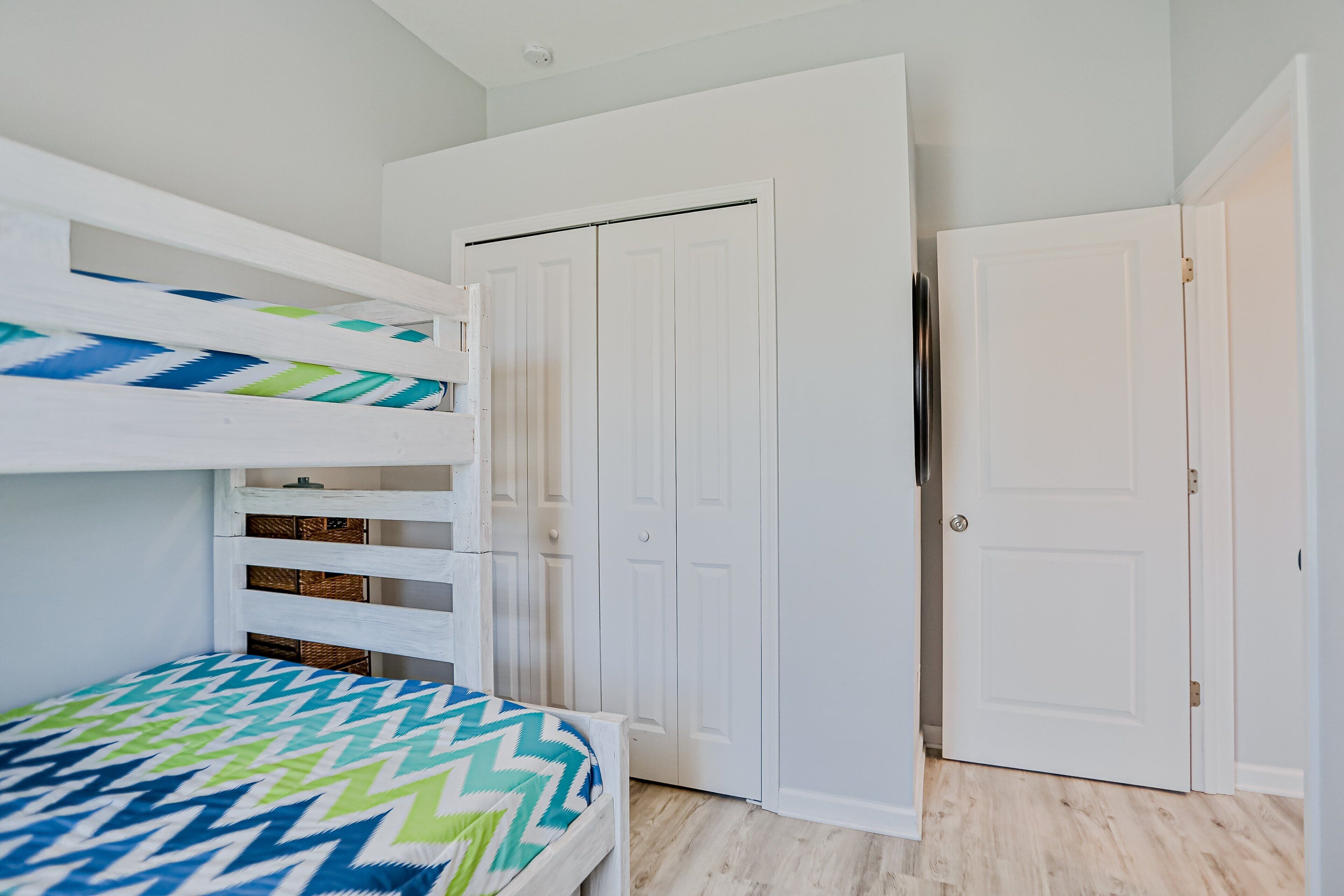 A room with a bunk bed, a wardrobe, and a door.