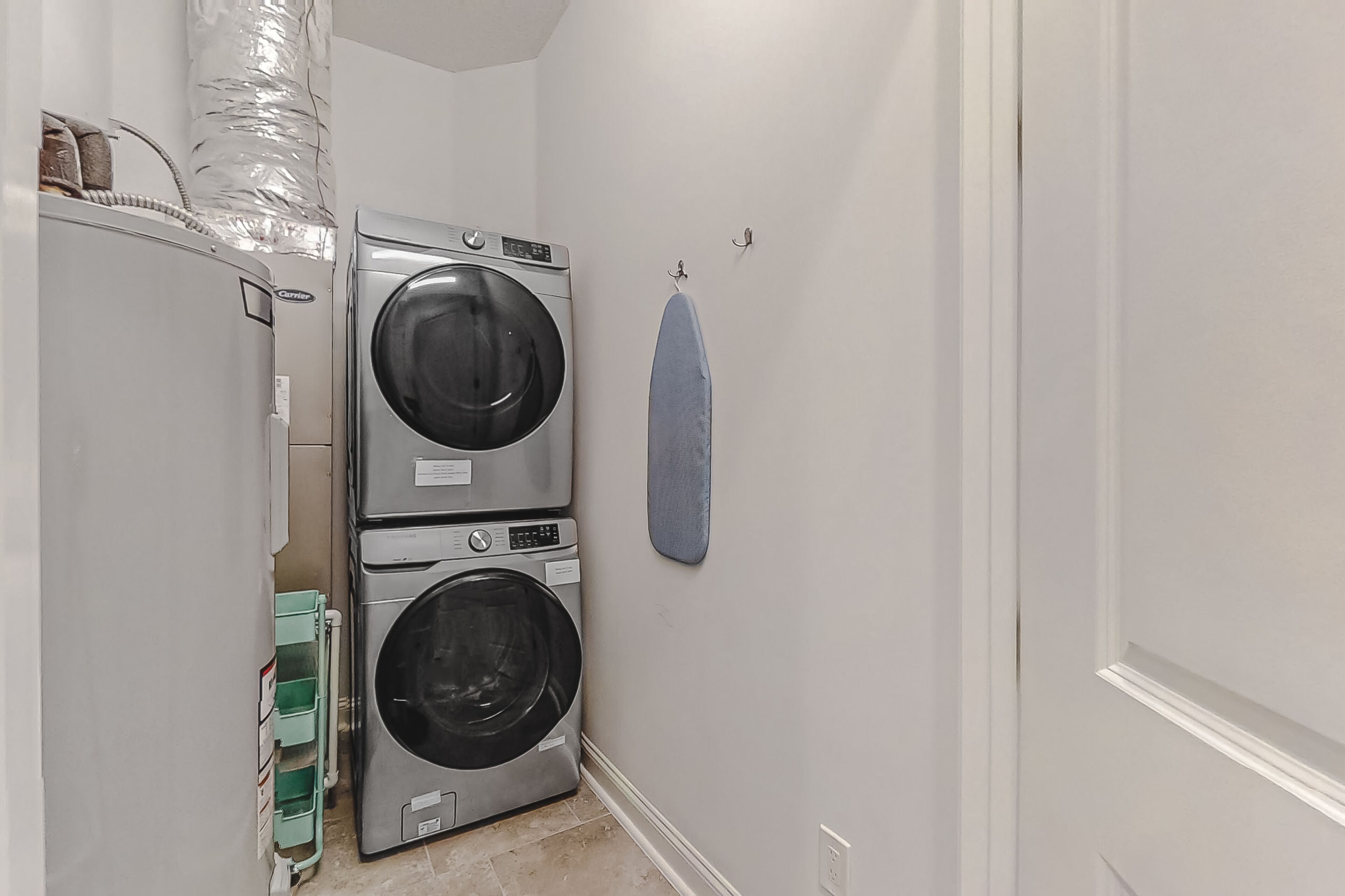 A laundry area with two stacked front-loading washing machines and a drying rack.