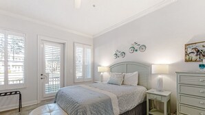 A bedroom with a bed, bedside tables, a bench, and a dresser. - Updated Townhome Near the Ocean W/private Patio, Shared Pool, Central A/C (Fernandina Beach)