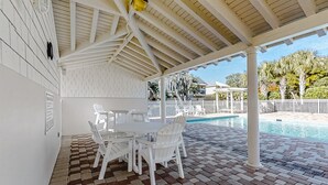 A covered patio with a pool, white furniture, and a brick floor. - Updated Townhome Near the Ocean W/private Patio, Shared Pool, Central A/C (Fernandina Beach)