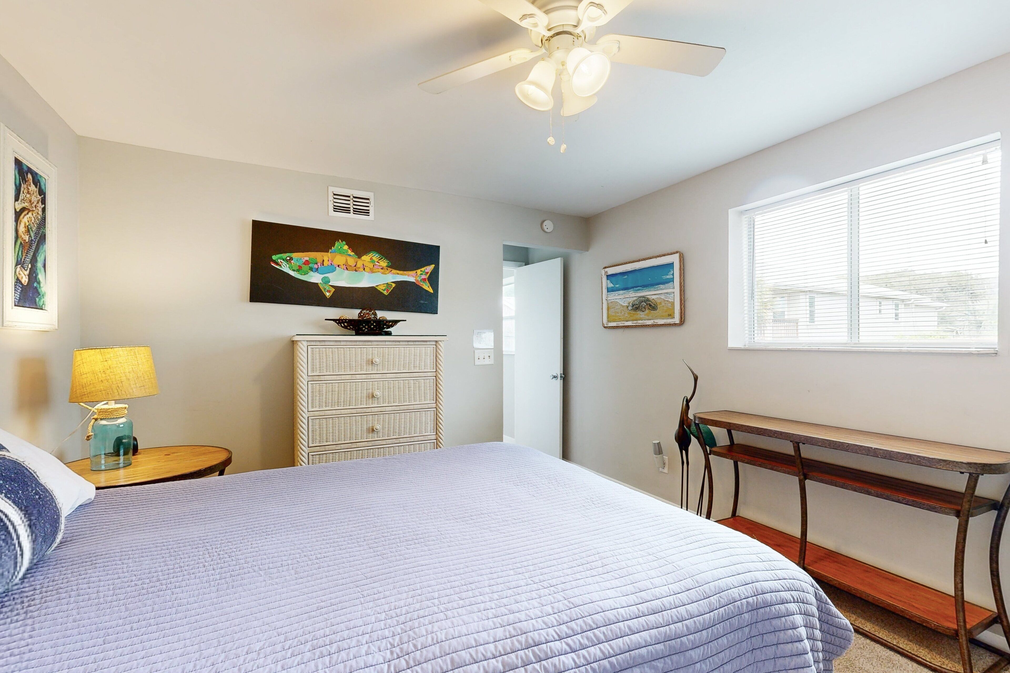 Une chambre à coucher comprenant un lit, un bureau, une commode et des œuvres d’art accrochées aux murs.