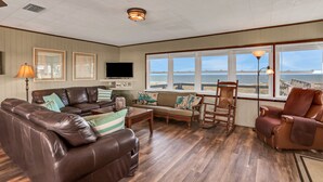 Ein Wohnzimmer mit einer Ledersofa, einem Holzstuhl und einem Fernseher.
