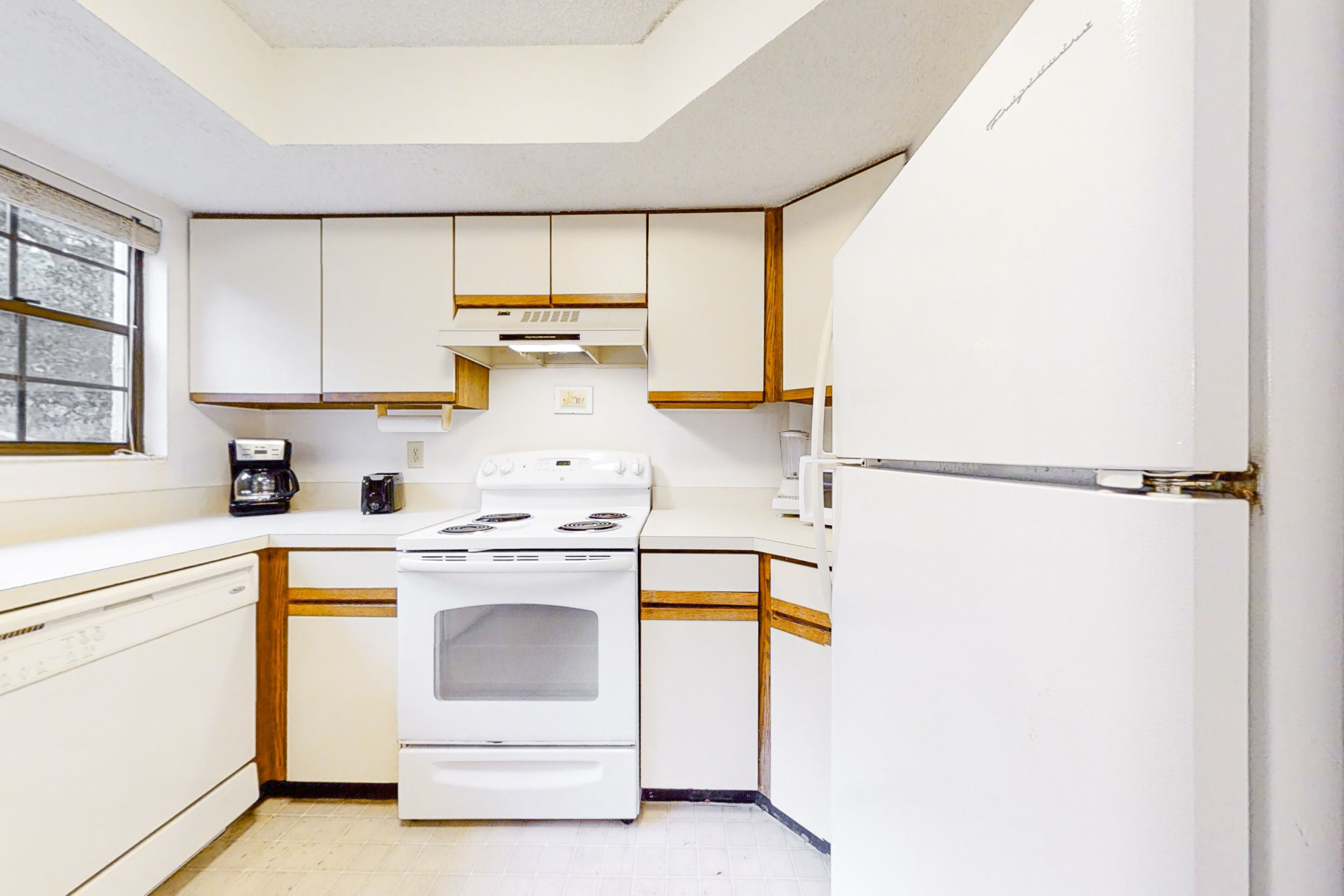 A compact kitchen with white cabinets, a stove, a microwave, and a refrigerator.