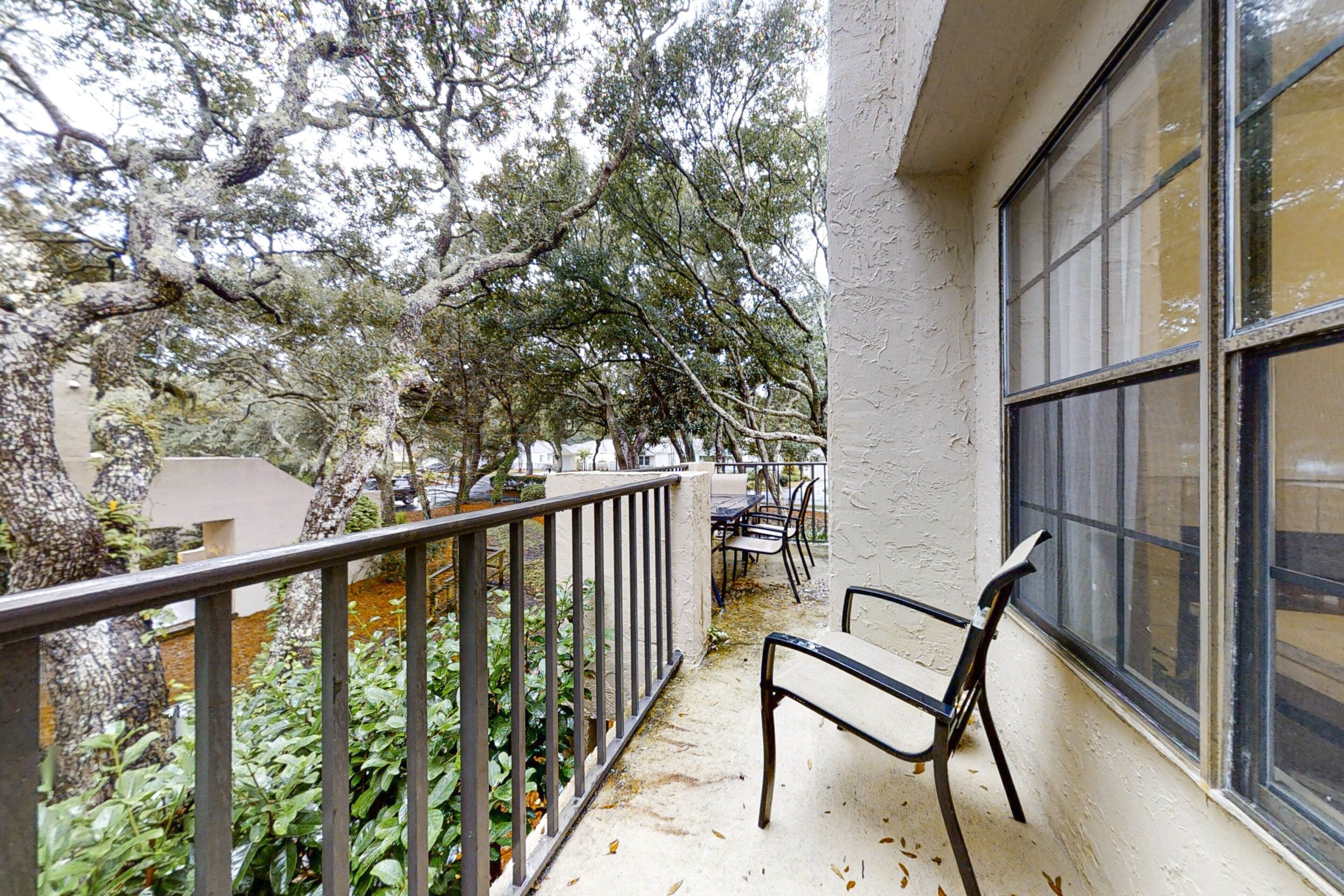 A balcony with a metal railing, a bench, and a table with chairs.