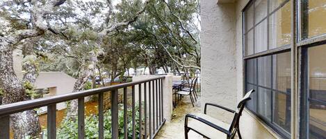 A balcony with a metal railing, a bench, and a table with chairs.
