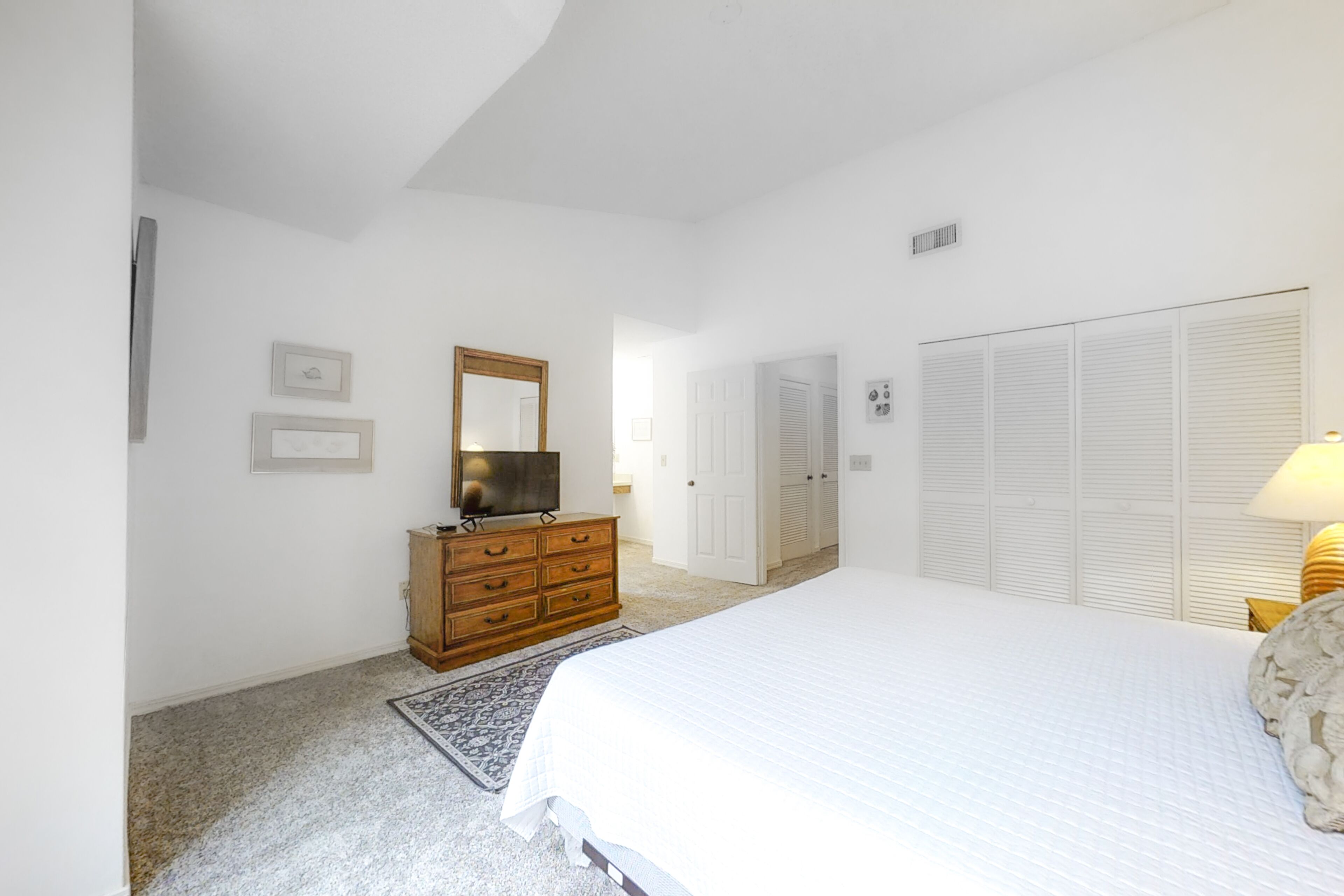 A bedroom with a bed, dresser, mirror, and closet.
