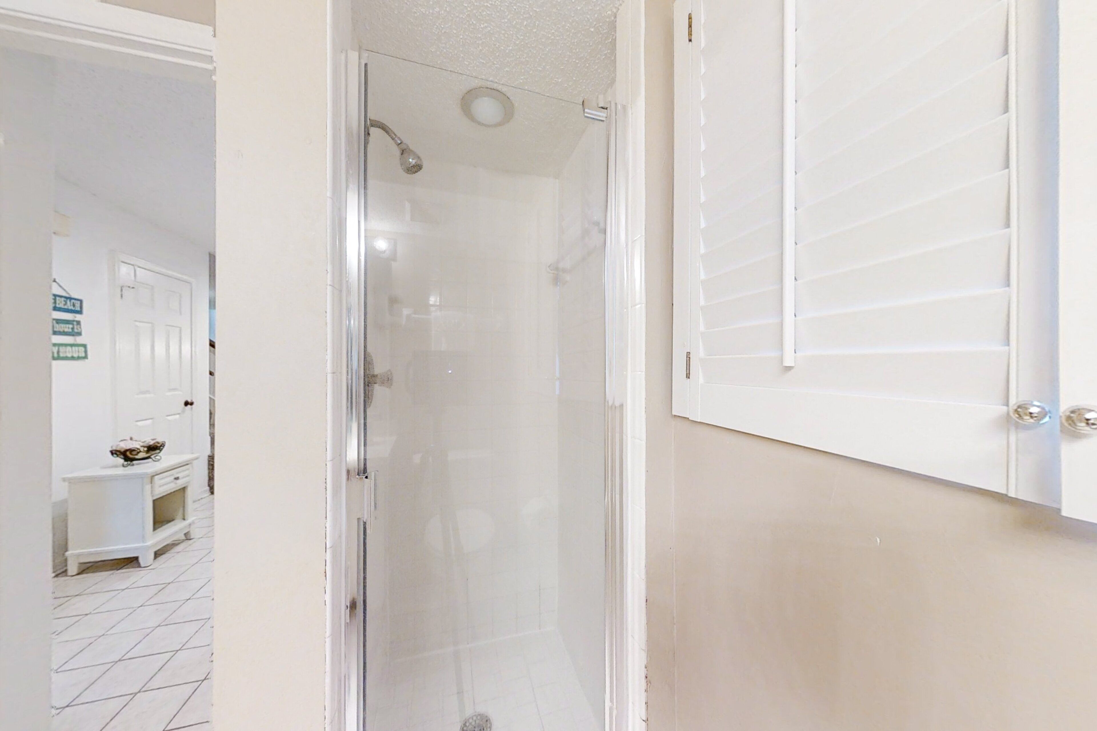 Un bagno con box doccia in vetro, un lavandino bianco e un mobile contenitore bianco.