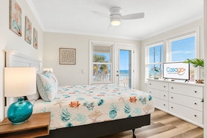 A bedroom with a bed, a nightstand, a TV, and a window with a view of the ocean. - Updated Home Across From Beach With Covered Balcony, Central AC, & Washer/dryer (Flagler Beach)