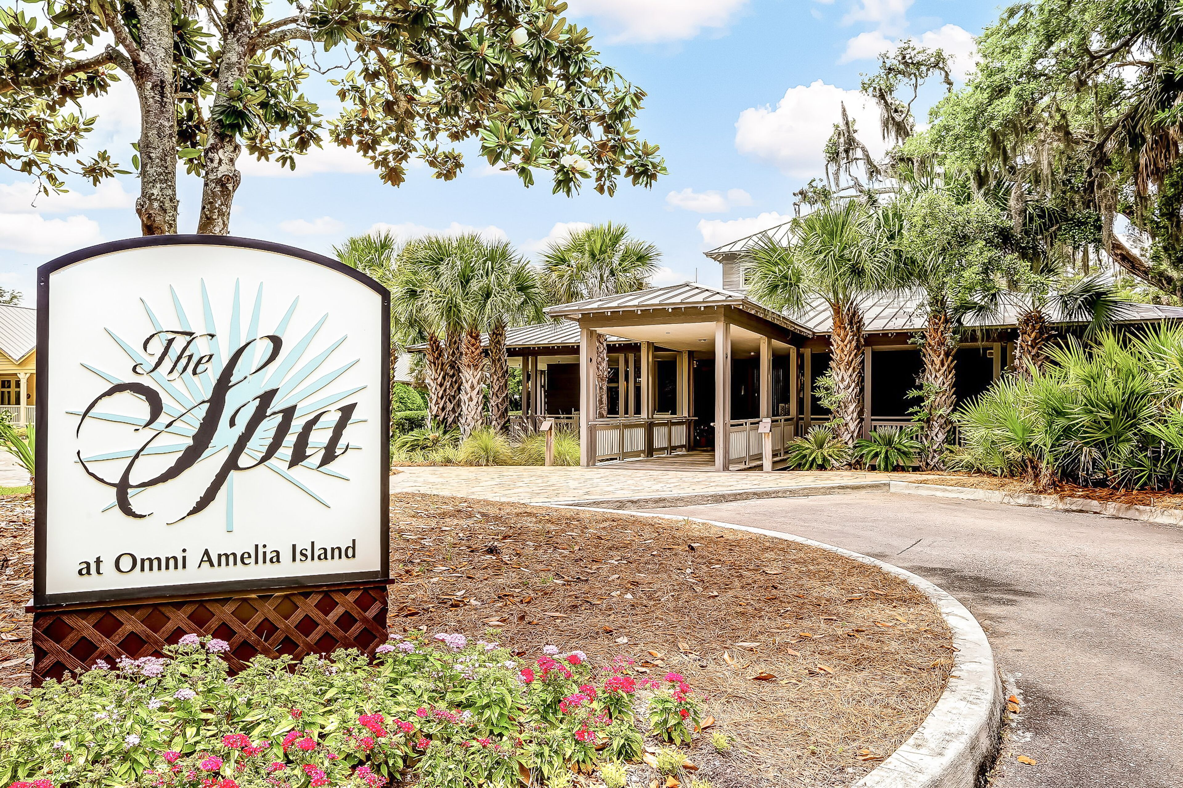Señalización de 'The Spa at Omni Amelia Island' con acceso cubierto y palmeras.